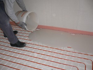 Screed being poured over panels and pipe